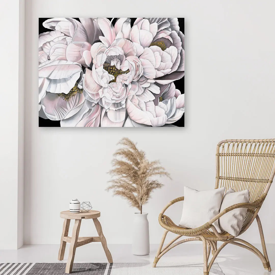 Floral artwork on a wall above a wicker chair and small table.