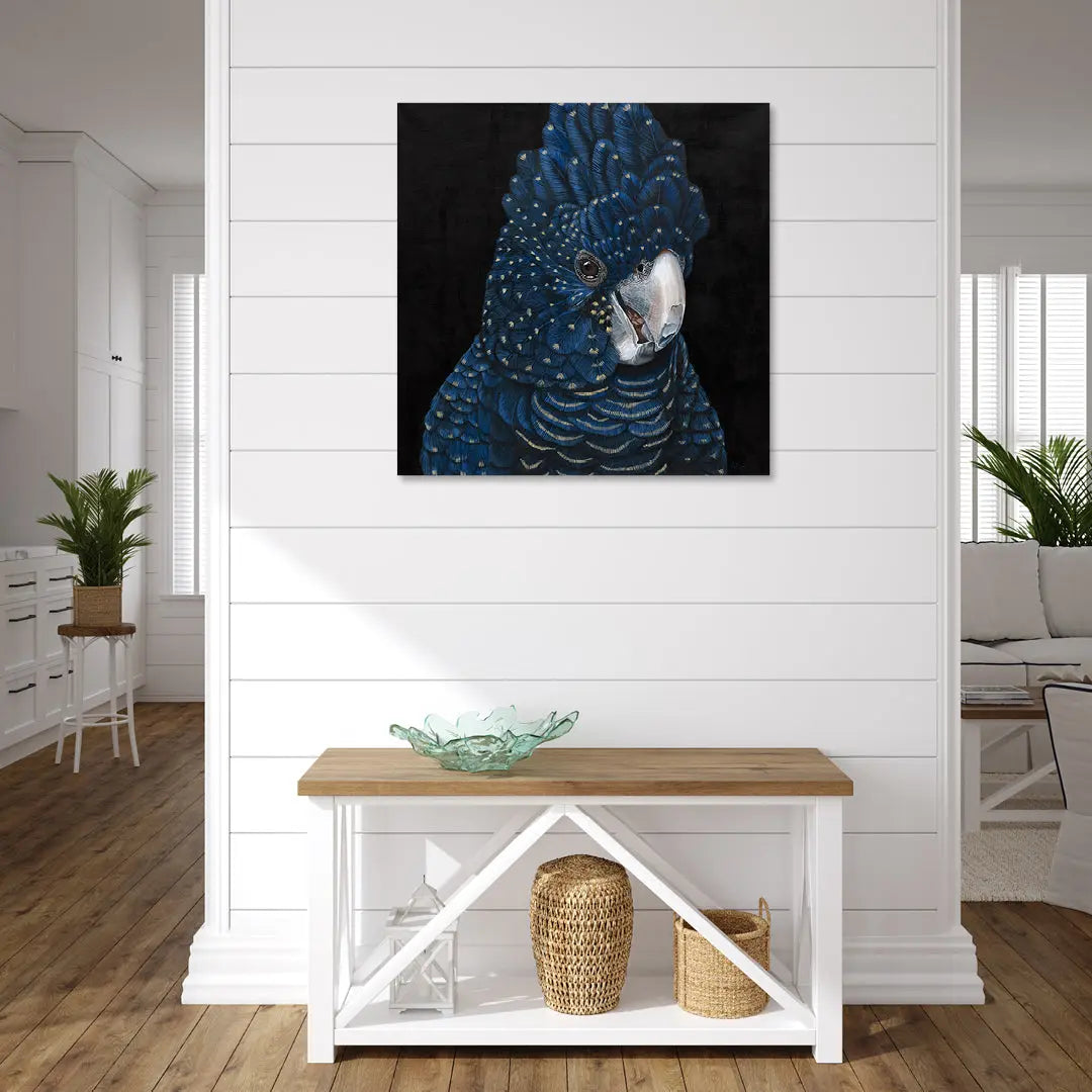 Blue parrot painting on a white wall above a wooden table with decorative items.