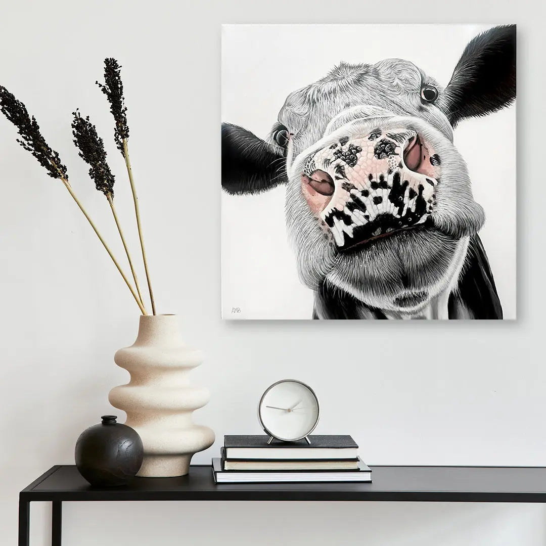 Canvas print of a cow's face on a wall above a table with decorative items.